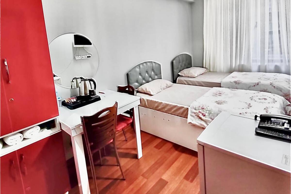 Ein Hotelzimmer mit Schreibtisch, zwei Betten, einem Kleiderschrank und einer Deckenleuchte.