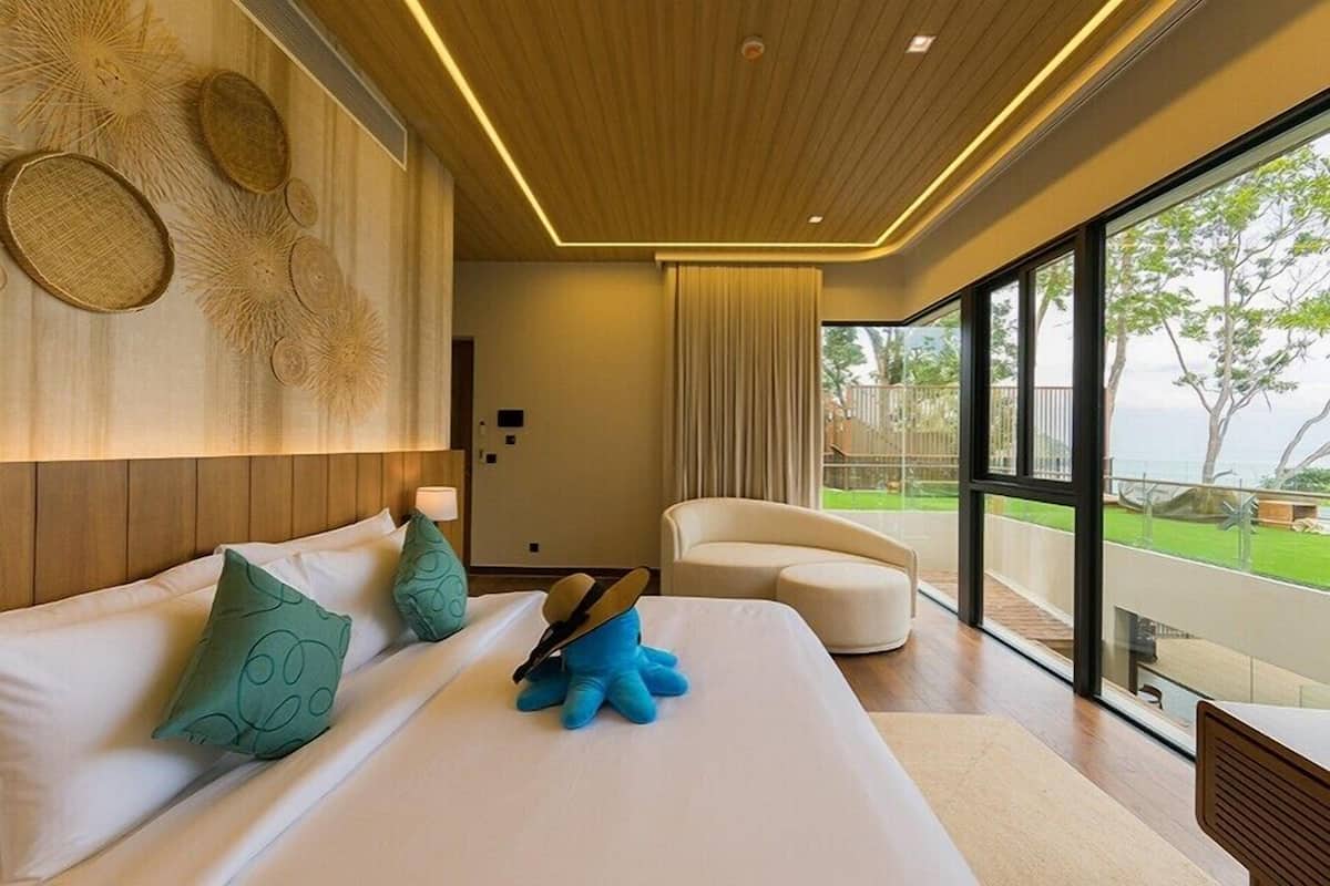 Un hotel moderno con una cama grande, un sillón blanco y vistas al exterior.