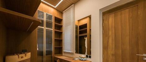 Una habitación compacta con escritorio de madera, una silla, armario empotrado y ventana con persianas.