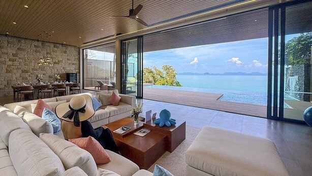 Un salón moderno con un sofá grande, una mesa de centro y vistas al mar.