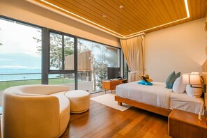 Un dormitorio moderno con un ventanal grande, una cama, un sofá y una mesita de noche.