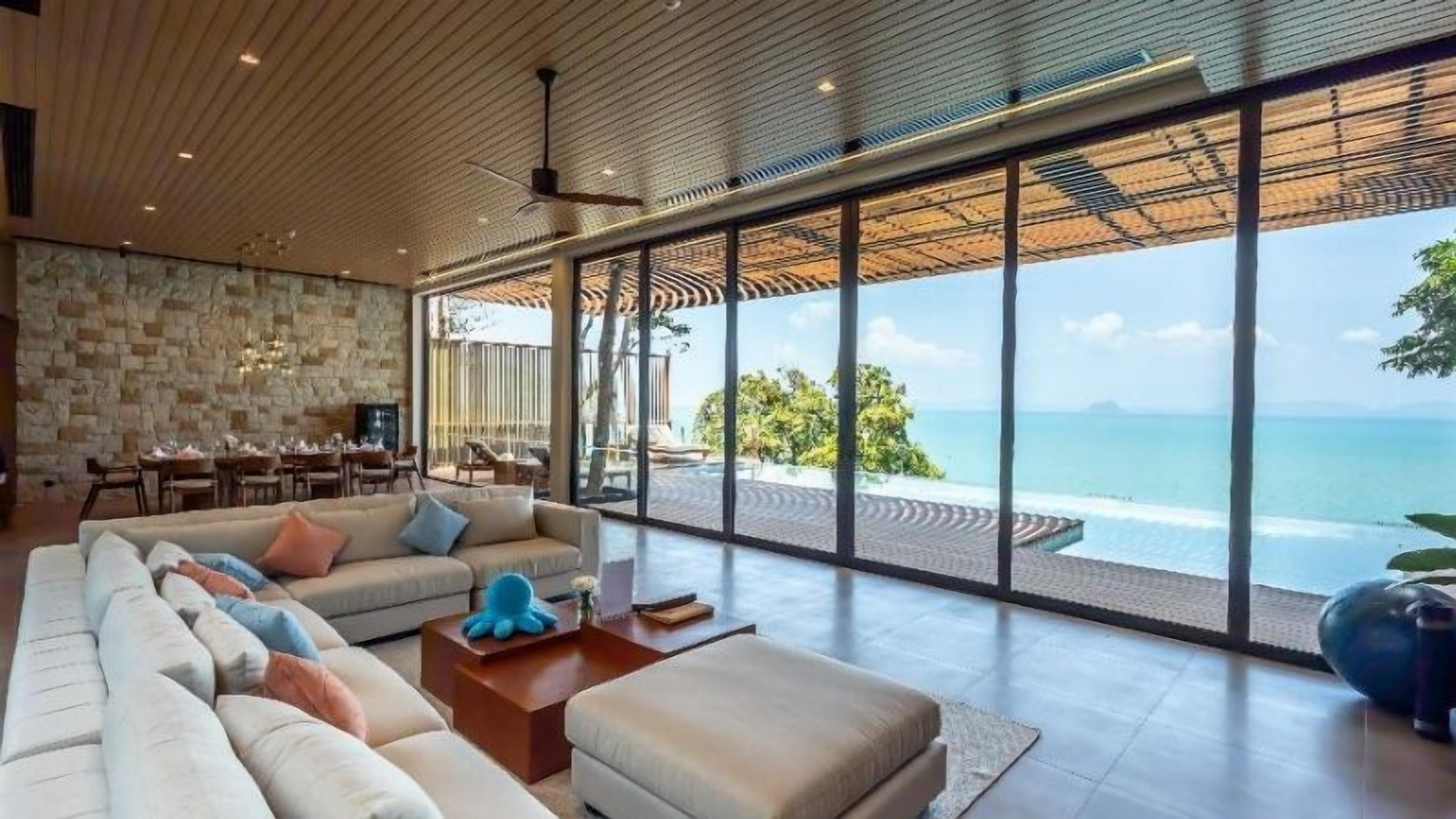 A modern living room with a large sofa, a coffee table, and a view of the ocean.
