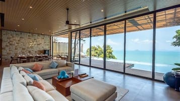 A modern living room with a large sofa, a coffee table, and a view of the ocean.