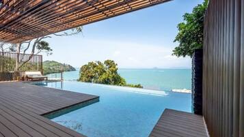 An infinity pool with a view of the sea and a wooden deck.