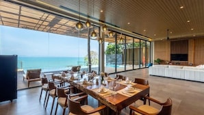 Un comedor con vista al océano, ventanas amplias y un diseño interior moderno.