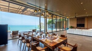 Un comedor con vista al océano, ventanas amplias y un diseño interior moderno.