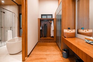 Un baño moderno con una bañera independiente, tocador de madera y un perchero para toallas.