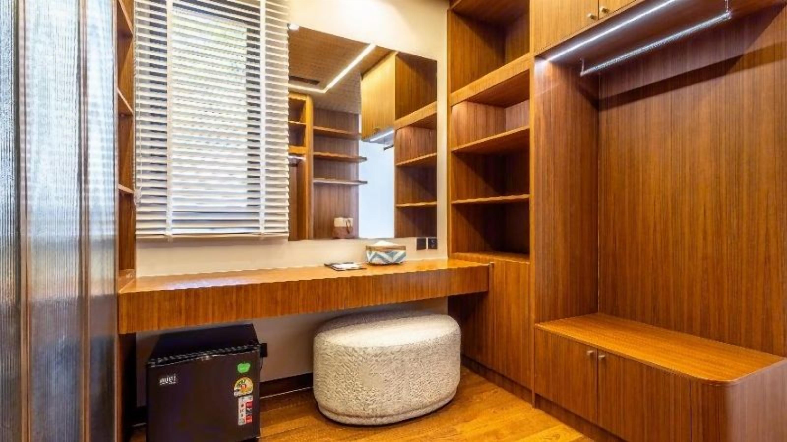A walk-in closet with wooden shelving, a mirror, and a bench.