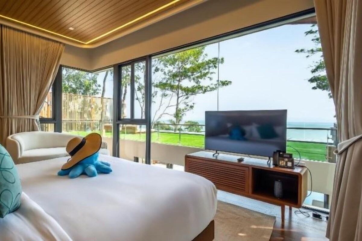Quarto com uma cama grande, televisão e vista para o mar.