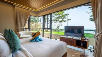 A bedroom with a large bed, a TV, and a view of the ocean.
