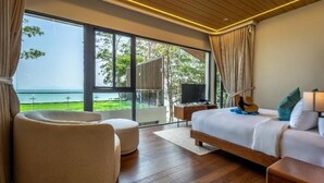 Un dormitorio con una ventana grande, una cama, una silla, una guitarra y un televisor.