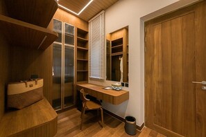 Quarto compacto com escrivaninha de madeira, cadeira, armário embutido e janela com persianas.