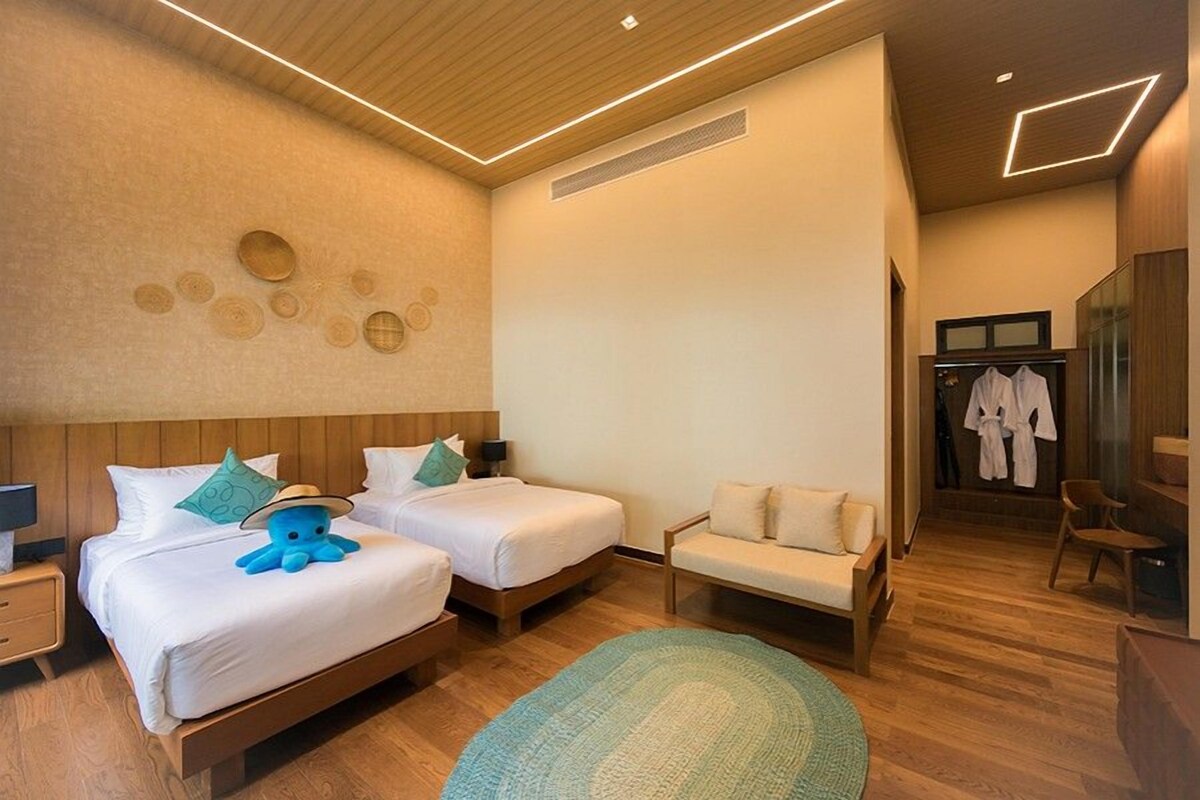Habitación de hotel con dos camas, un sofá, una mesita y un espejo.