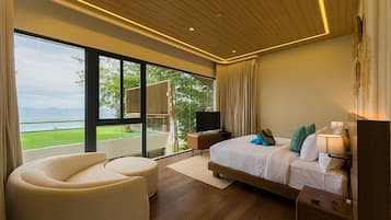 A modern bedroom with a large bed, a sofa, a TV, and a balcony with a view.