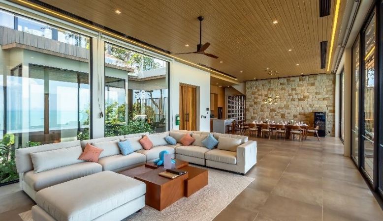 A modern living room with a sectional sofa, a coffee table, and a dining area with chairs and a table.