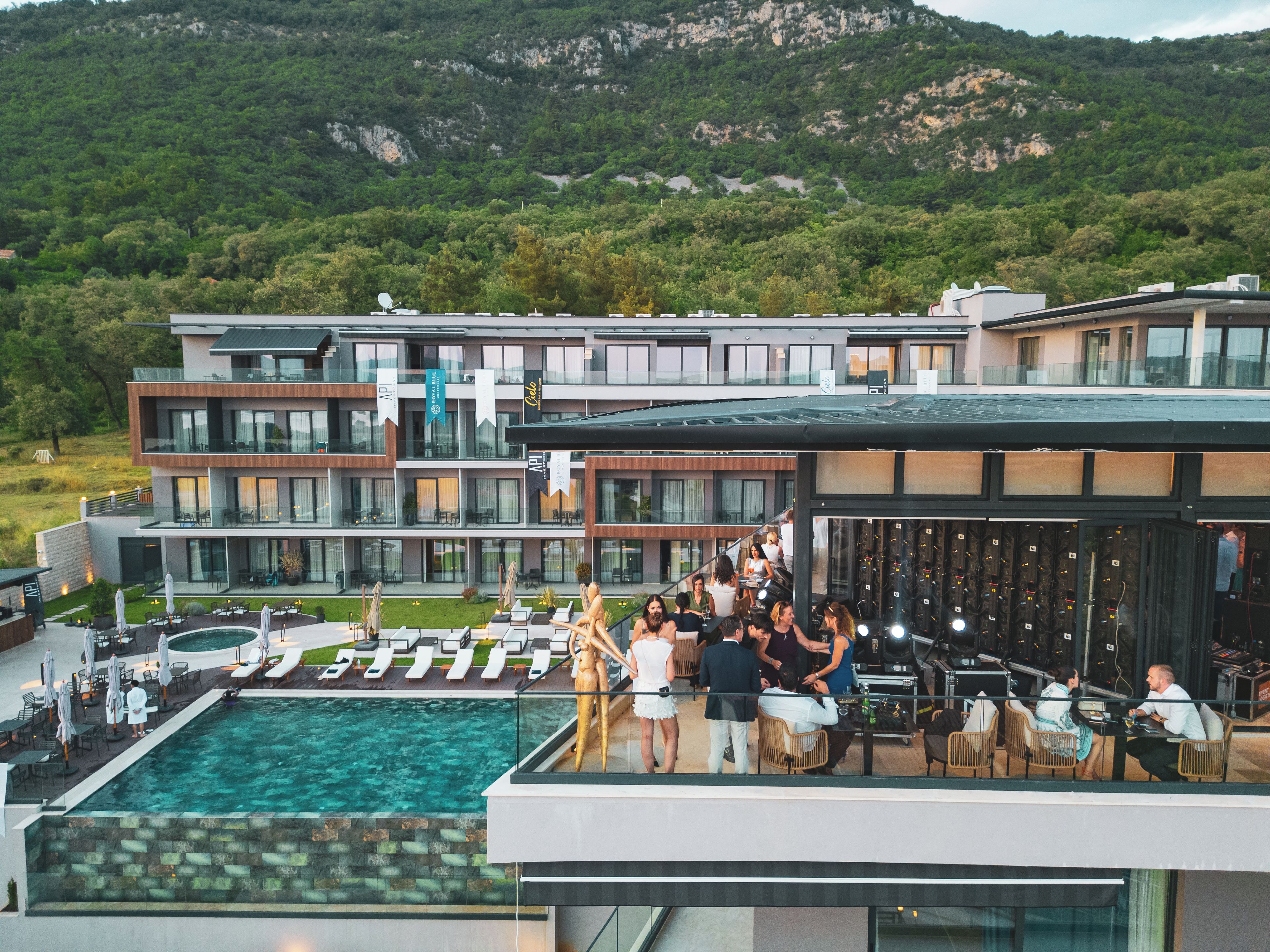 Un hôtel moderne doté d’une piscine sur le toit, d’un espace extérieur aménagé et offrant une vue sur un paysage montagneux.
