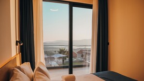 Una habitación de hotel con una cama, vistas a un balcón y un vistazo al paisaje exterior.