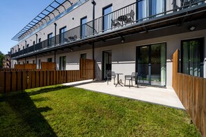 A modern building with a flat roof, large windows, and a balcony with outdoor seating. - Royal Blue Resort And Residences (Kotor)