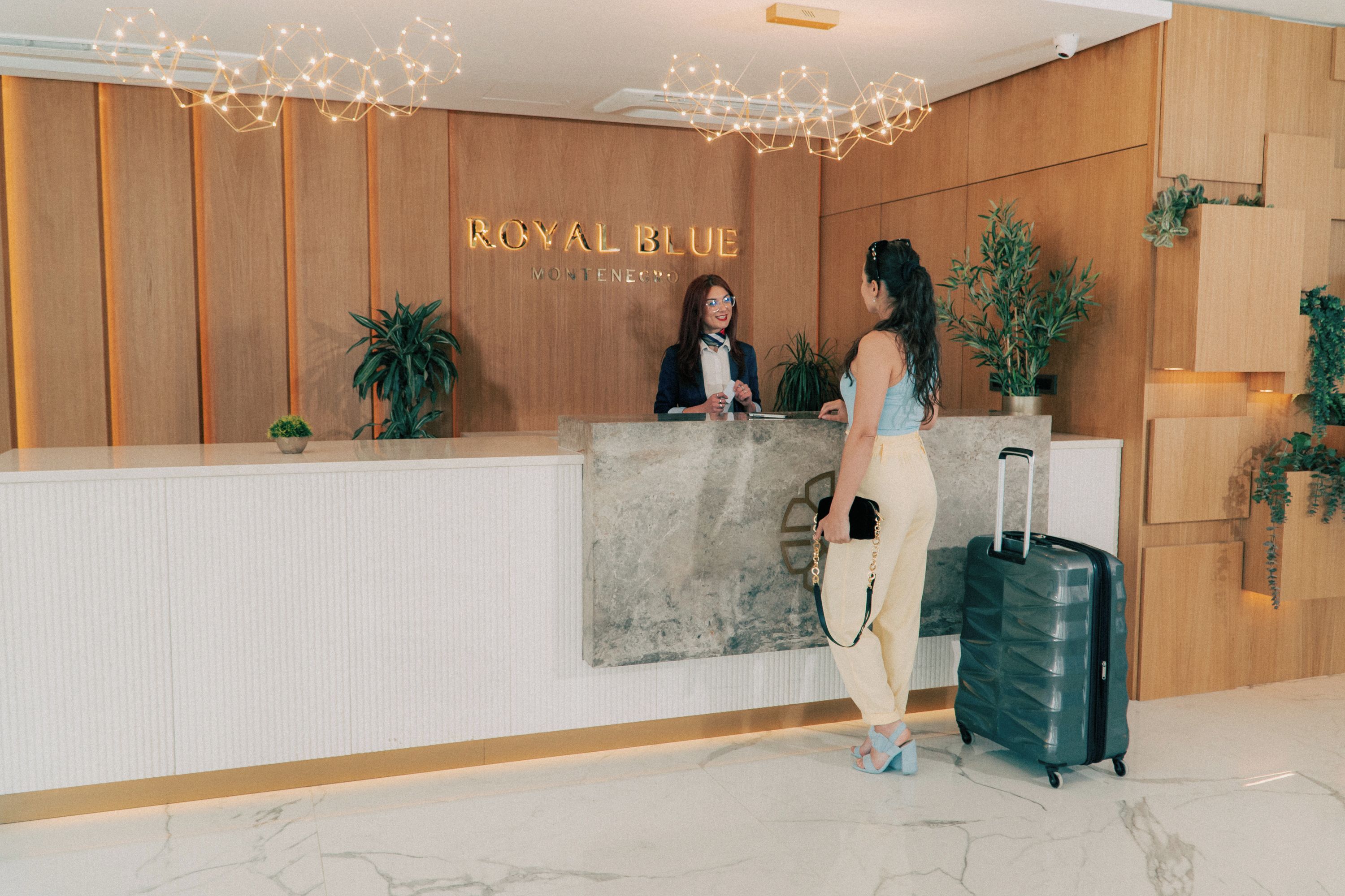 A reception desk with a wooden panel wall, a reception desk with a marble top, and a potted plant.