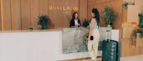 A reception desk with a wooden panel wall, a reception desk with a marble top, and a potted plant.