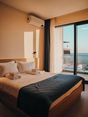 Habitación de hotel con cama, ventana que ofrece vistas a una piscina y edificios, y un equipo de aire acondicionado en la pared.
