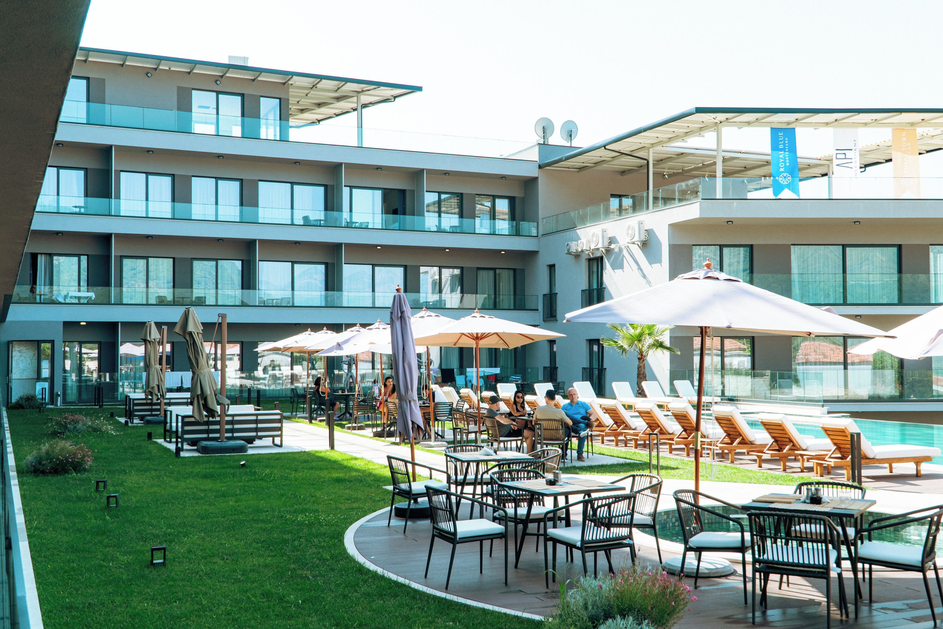 Et hotel med udendørs siddepladser, swimmingpool og en moderne bygningsfacade.