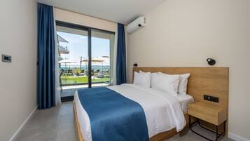 Ein Hotelzimmer mit Bett, Nachttisch, Fenster mit Vorhängen und einer Klimaanlage.