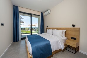Una habitación de hotel con una cama, una mesita de noche, una ventana con cortinas y un equipo de aire acondicionado.