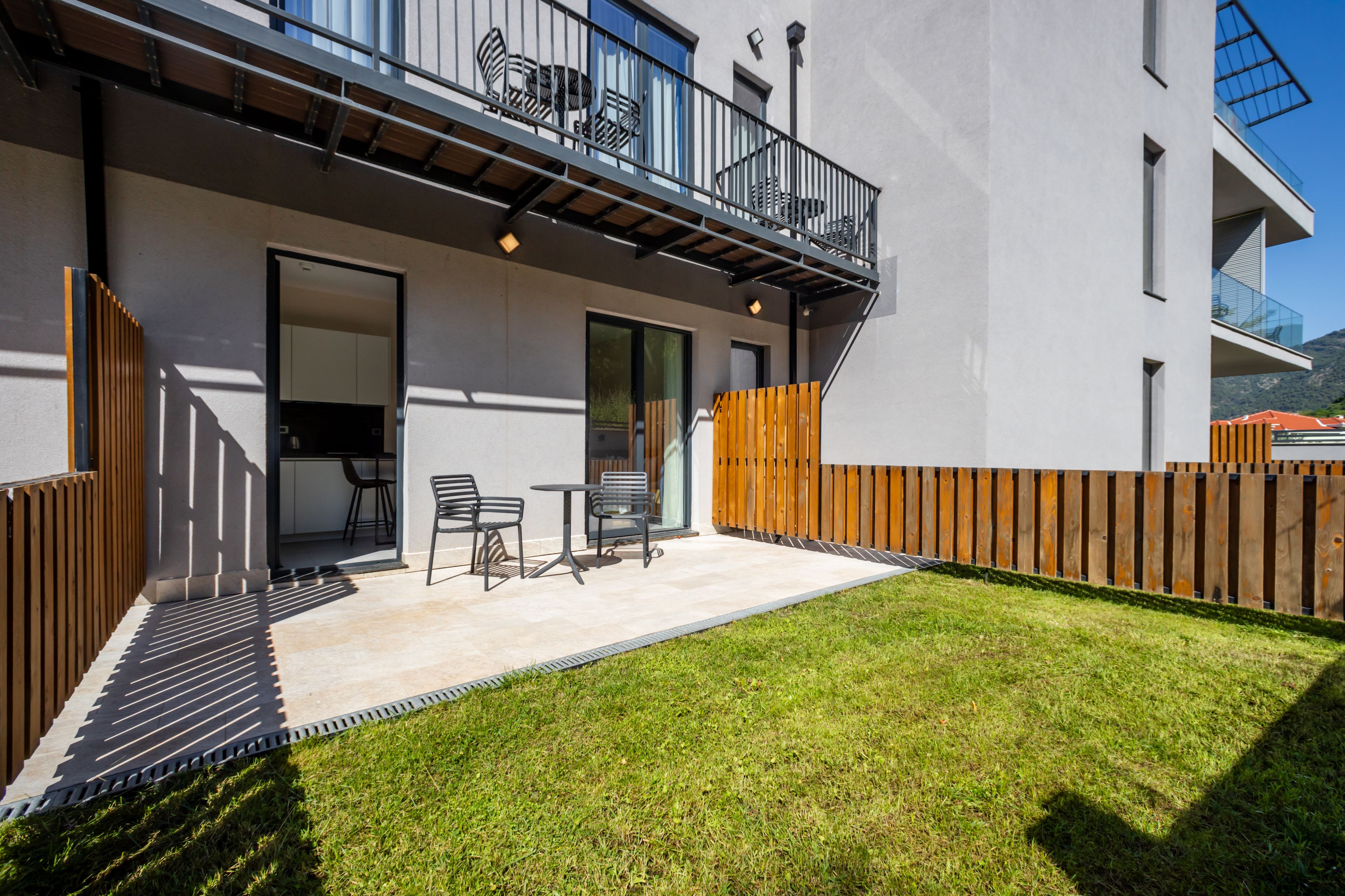 Ein modernes Gebäude mit Balkon, Sitzgelegenheit im Freien und einem gepflegten Rasen.