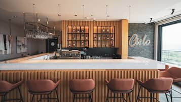 A modern bar area with a wooden bar counter, bar stools, and a neon sign.