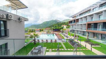 A modern hotel with a rooftop pool, outdoor seating, and mountain views.