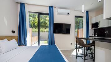 A hotel room with a bed, a desk, a TV, and a view of the outdoors.