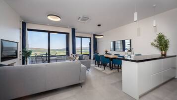 A modern kitchen with a dining area, large windows, and a view of the landscape.