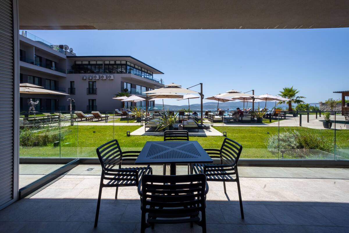 Un balcón con mobiliario exterior, piscina y vista al mar.