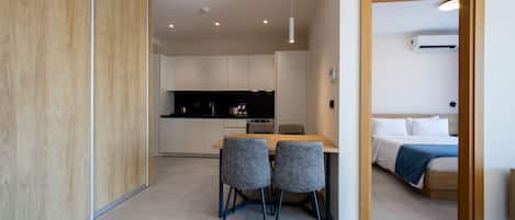 A modern interior with a dining area, kitchen, and bedroom.