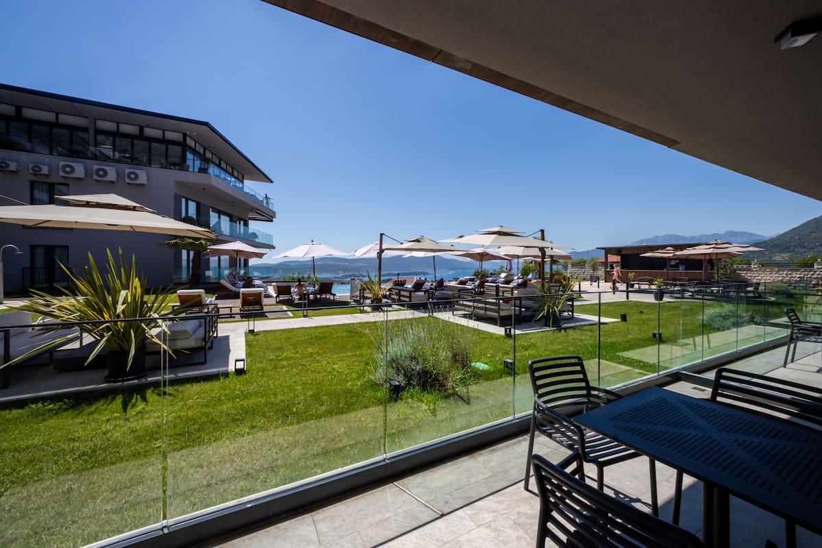 Un balcón con mobiliario exterior, vistas al mar y un edificio de varios pisos.