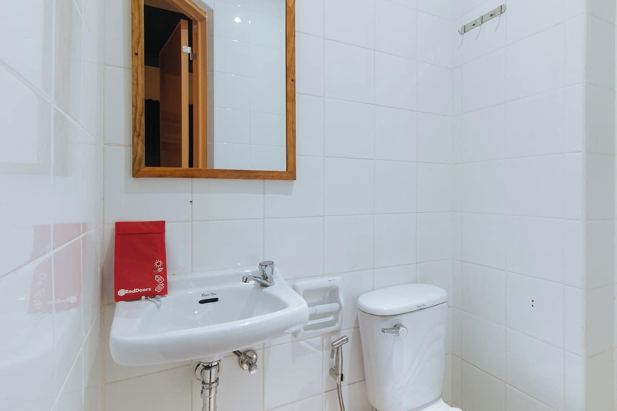 Un baño con lavamanos blanco, inodoro y espejo.