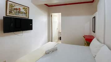 Ein Hotelzimmer mit einem Bett, einem an der Wand montierten Fernseher und einem Gemälde über dem Bett.