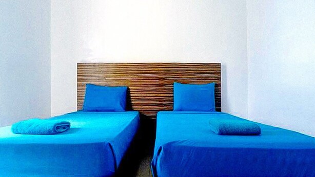 A room with two beds, each with a blue bedspread and pillow, and a wooden headboard. - Reddoorz @ Sir G Hotel D'mall Boracay (Boracay Island)