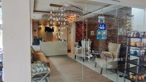 A reception area with a modern chandelier, a reception desk, and a glass wall with a view of the interior. - Reddoorz @ Sir G Hotel D'mall Boracay (Boracay Island)