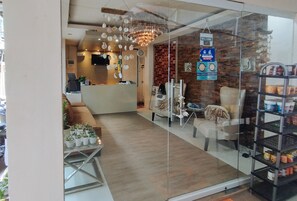 A reception area with a modern chandelier, a reception desk, and a glass wall with a view of the interior. - Reddoorz @ Sir G Hotel D'mall Boracay (Boracay Island)