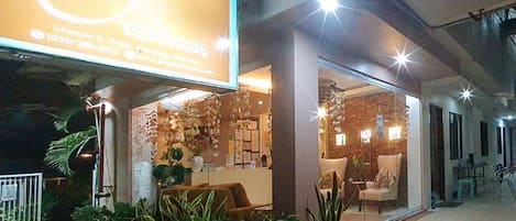 A storefront with a large illuminated sign, a reception area with a counter, and a seating area with chairs and tables.