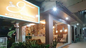 A storefront with a large illuminated sign, a reception area with a counter, and a seating area with chairs and tables. - Reddoorz @ Sir G Hotel D'mall Boracay (Boracay Island)