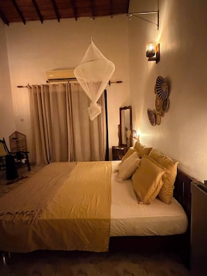 A bedroom with a bed, curtains, a hanging canopy, wall-mounted lights, and decorative wall art. - Riverbank Bentota (Aluthgama)