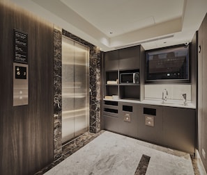 Un baño moderno con suelo de mármol, lavabo empotrado, espejo y panel de control digital del ascensor.