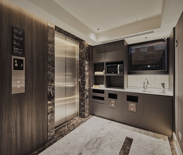 A modern bathroom with a marble floor, a built-in sink, a mirror, and a digital elevator panel. - Orange Hotel - Hanzhong Taipei (Taipei)