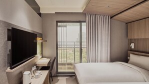 A modern hotel room with a flat-screen TV, a bed, a desk with a coffee maker, and a large window with a view of buildings. - Orange Hotel - Hanzhong Taipei (Taipei)