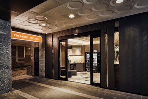 The entrance to the Orange Hotel with a modern design, including a sign, a reception desk, and a vending machine. - Orange Hotel - Hanzhong Taipei (Taipei)