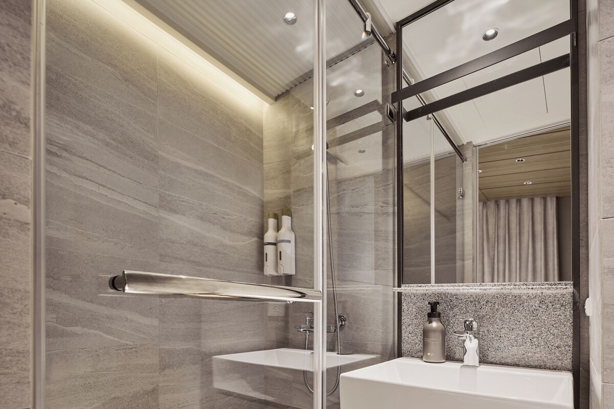 A modern bathroom with a glass shower enclosure, a vanity with a mirror, and a towel rack.