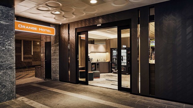 The entrance to the Orange Hotel with a modern design, including a sign, a reception desk, and a vending machine. - Orange Hotel - Hanzhong Taipei (Taipei)